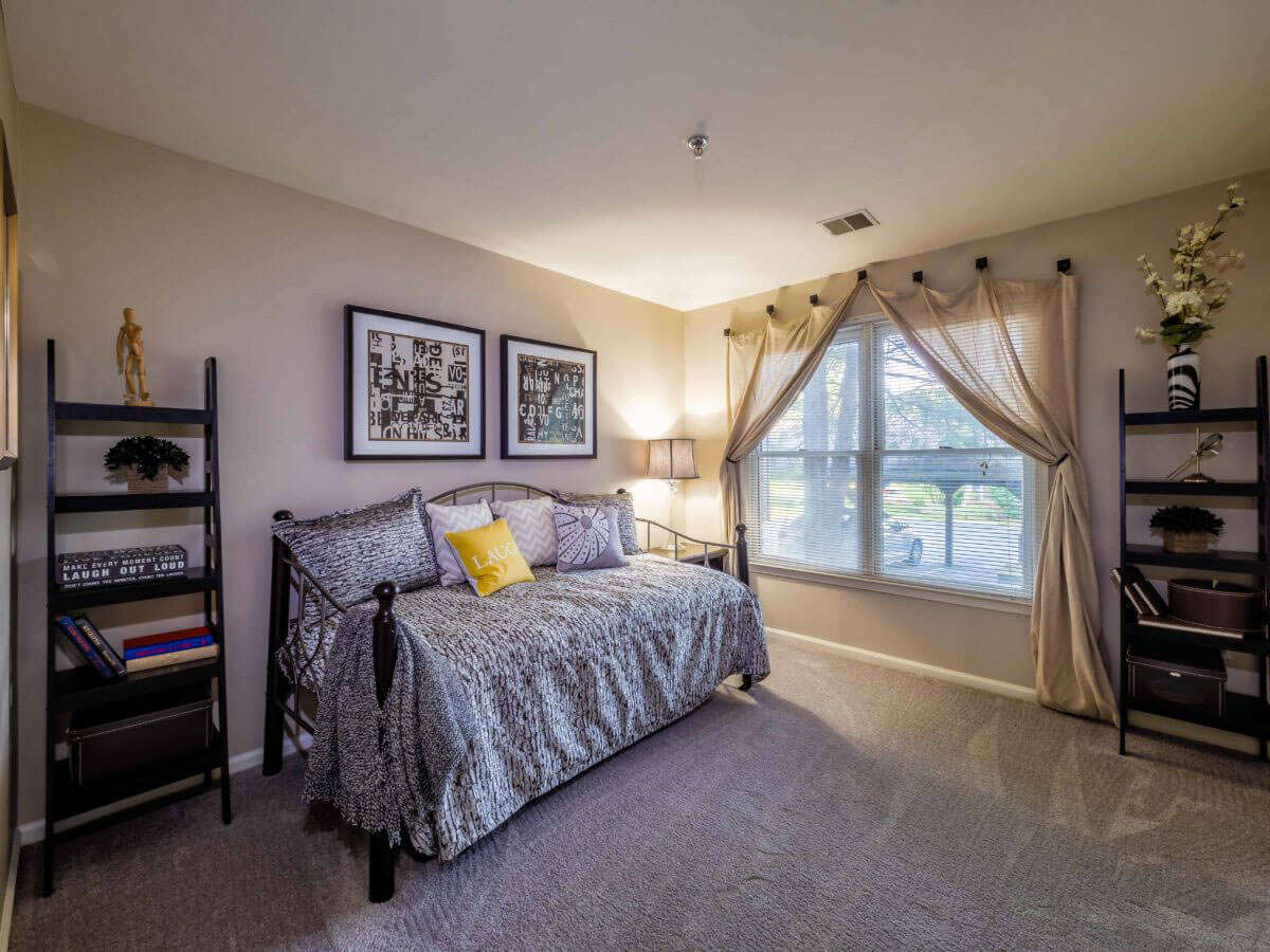 Spectacular model bedroom with carpeted flooring and large window in Pointe North apartment for rent